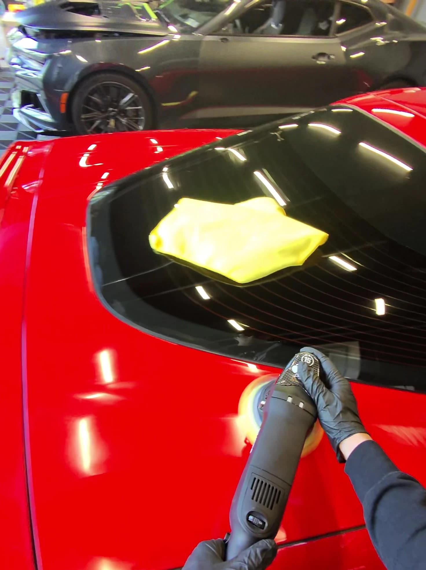 Machine polisher working on the red rear quarter of a Corvette C6