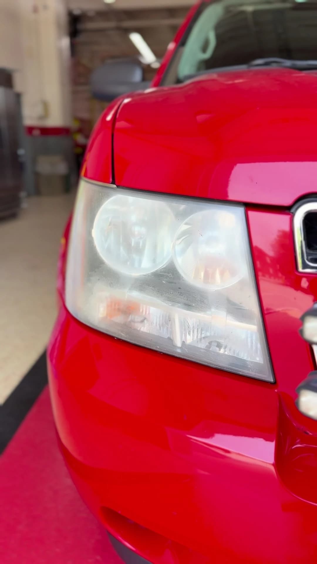 Cloudy headlight lens on a red truck before restoration
